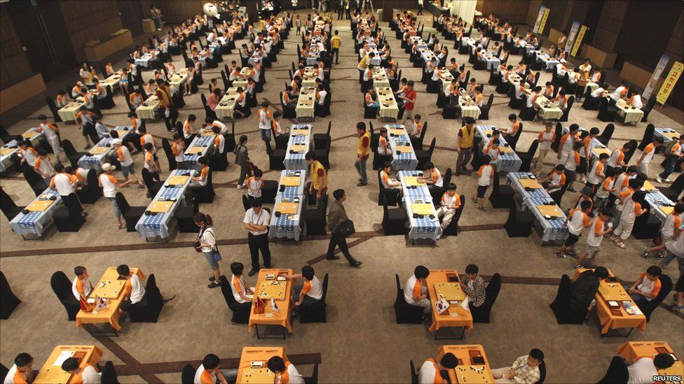 Large international Go tournament with hundreds of players seated at tables and playing Go simultaneously