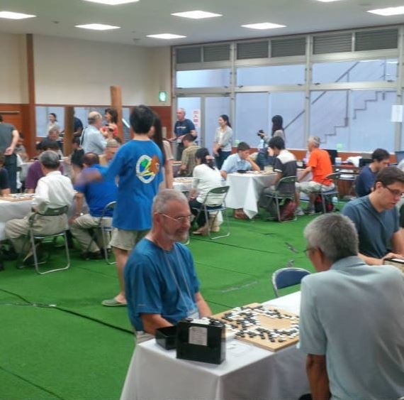Large room with many people playing Go at tables during Osaka Go Camp