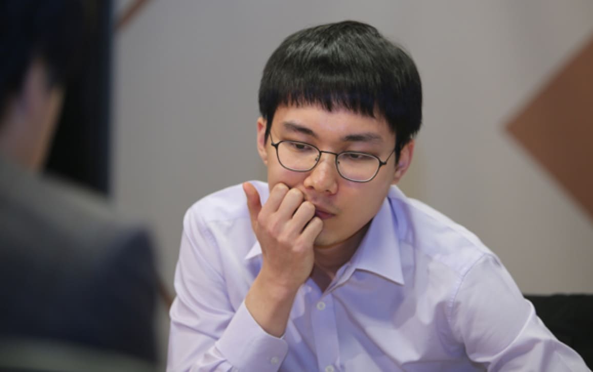 South Korean Go player Park Junghwan in deep concentration during a game, wearing glasses and a white shirt.