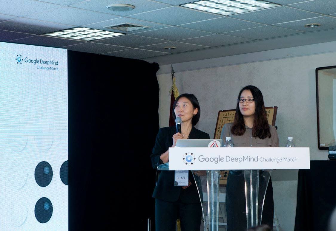 Professional Go player Hajin Lee speaking on stage during the Google DeepMind Challenge Match, analyzing AlphaGo vs Lee Sedol