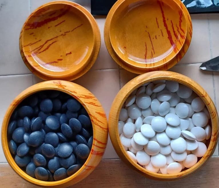 Glossy black and white Go stones in lacquered bowls with matching lids.
