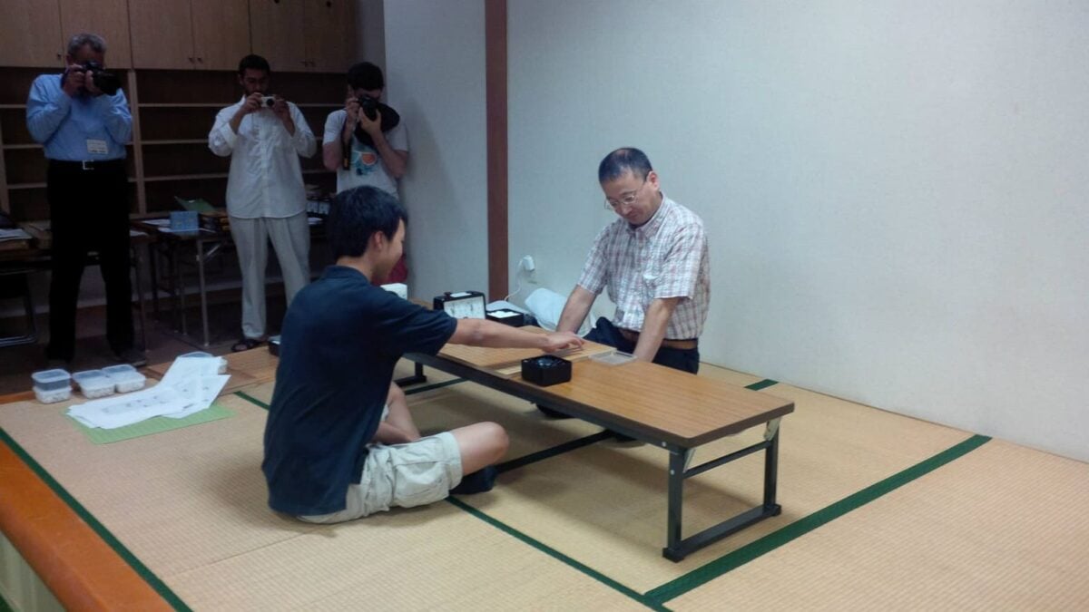 Instructor playing a simultaneous Go game against seated participants in a tatami room