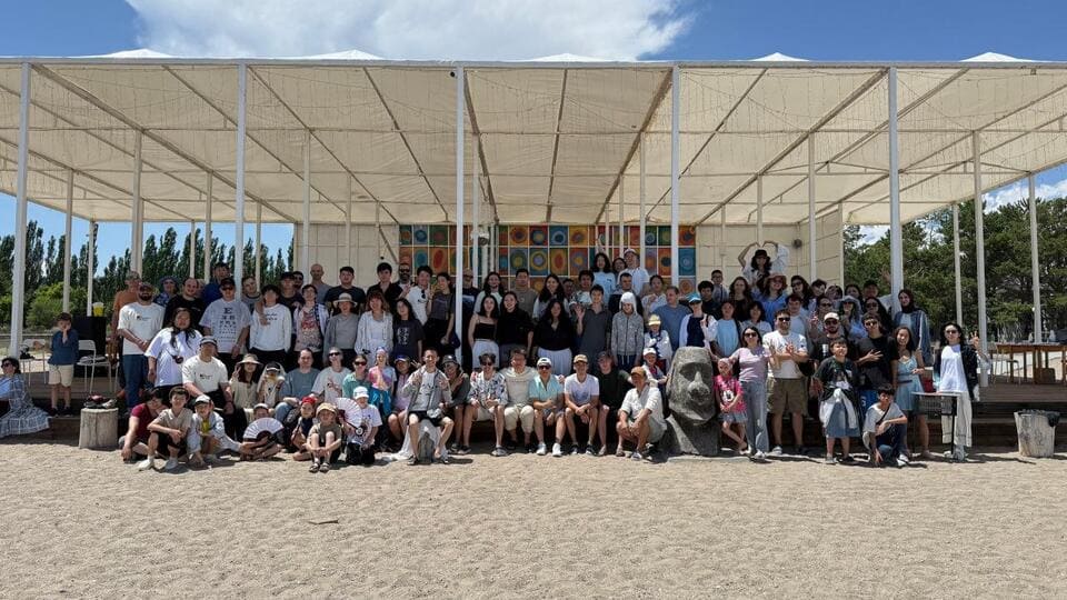 Large group photo of Issyk-Kul Cup participants gathered by the beach pavilion near Lake Issyk-Kul.