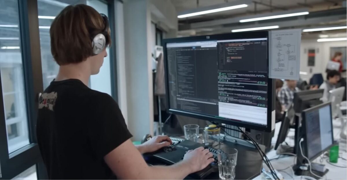 Developer working at a computer with code and Go board analysis related to AlphaGo development