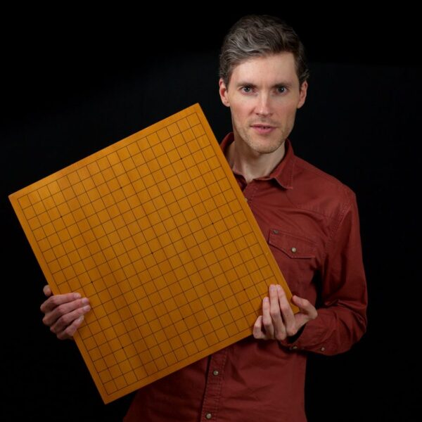 Man presenting a full-sized Go board with a serious expression
