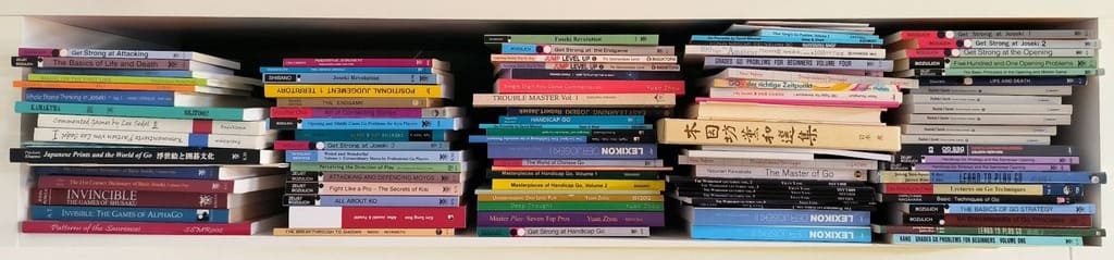 A full shelf of Go books featuring joseki, opening theory, and famous games.