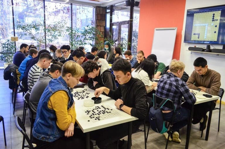 A busy classroom full of young players deeply focused on Go matches during a local tournament in Kyrgyzstan.