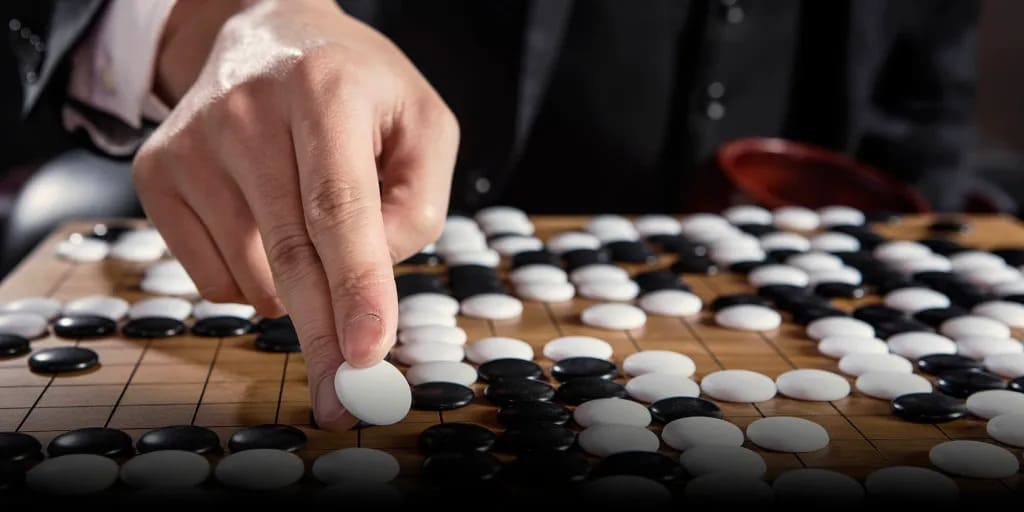 Close-up photo of a hand placing a white stone on a crowded Go board during play.