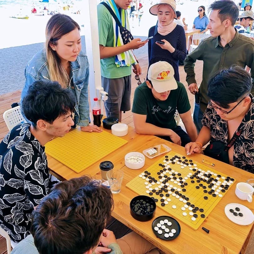 A group of players deeply focused during a Go match at a seaside tournament.