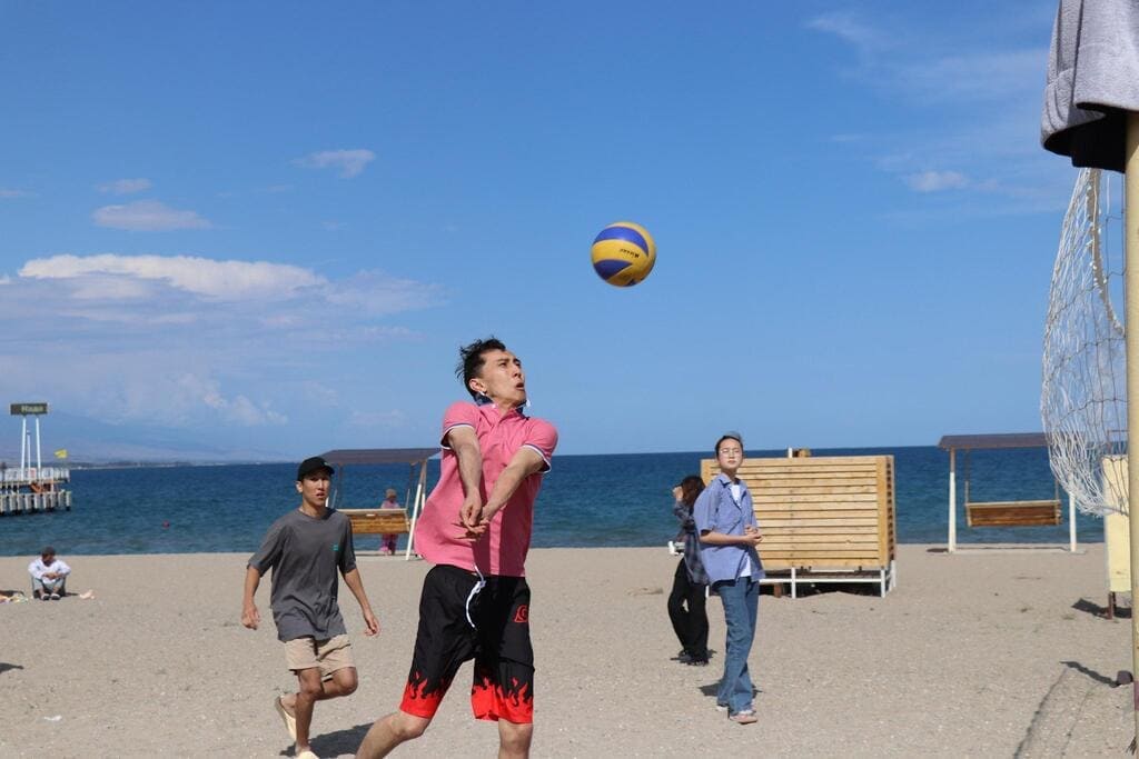 Young players enjoying a game of beach volleyball near the sea.