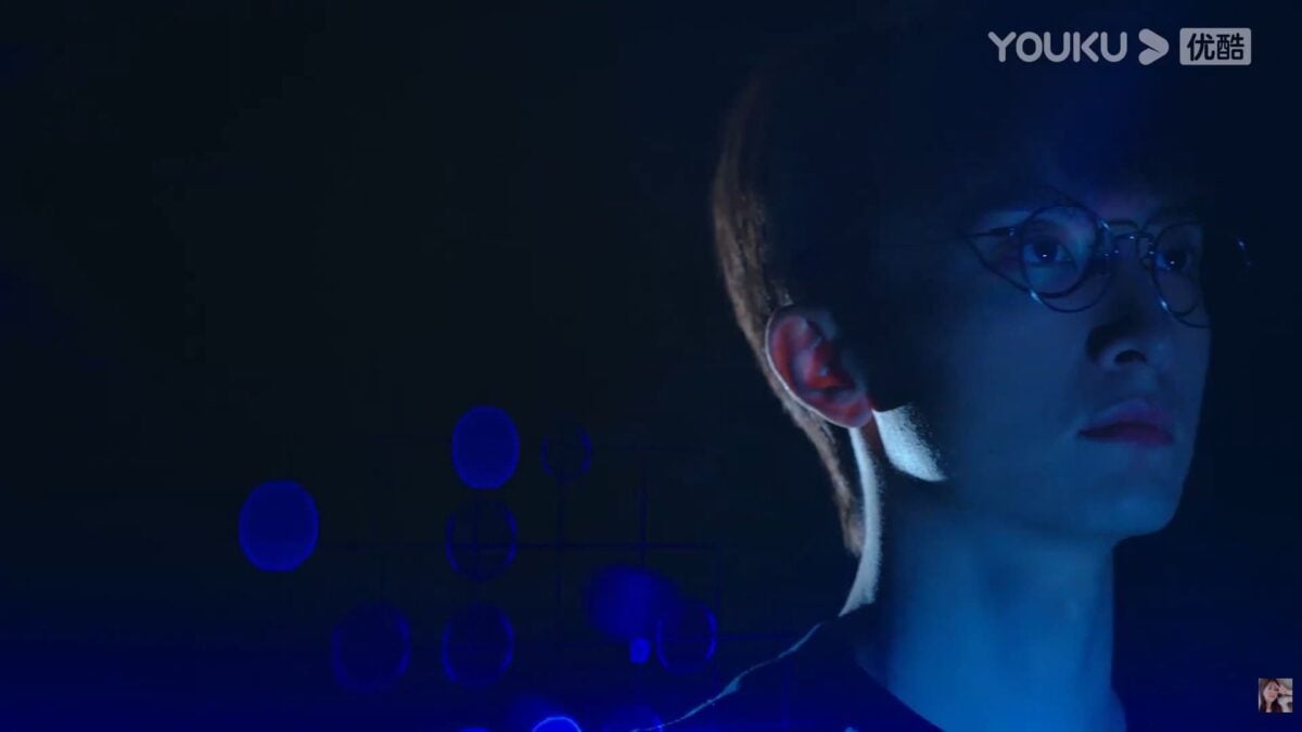 A blue-lit close-up from GO Into Your Heart showing a man in glasses thinking intensely.