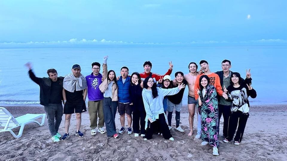 A cheerful group of festival participants posing for a photo by the lake during sunset.