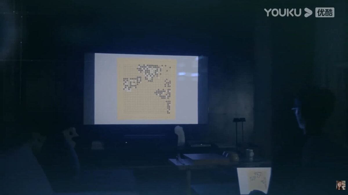 A dark interior scene from GO Into Your Heart with a projected image of a Go board arranged to resemble a QR code.