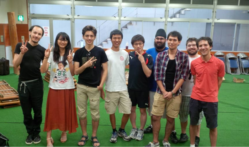 Group of international Go camp participants posing together indoors after an event.