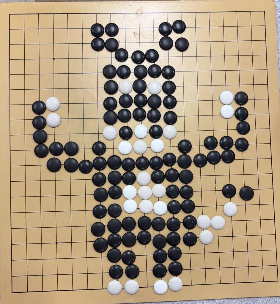 A Go board with black and white stones arranged into the shape of a horse as a humorous visual example.