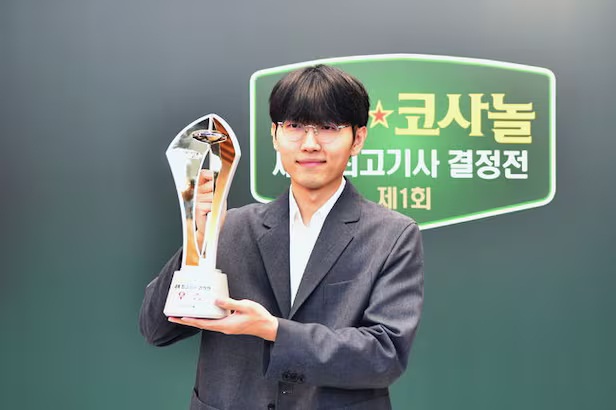 Go tournament winner holding a trophy on stage after a championship match