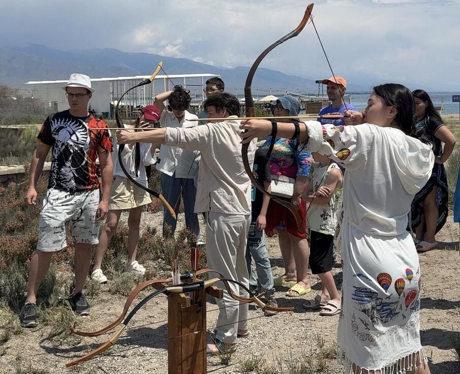 Festival participants practicing archery outdoors near Lake Issyk-Kul as part of the event program.