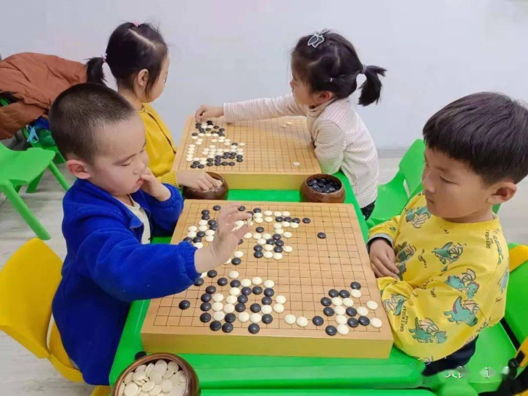 A group of children playing Go on small boards in a colorful classroom, learning strategy and patience through Baduk
