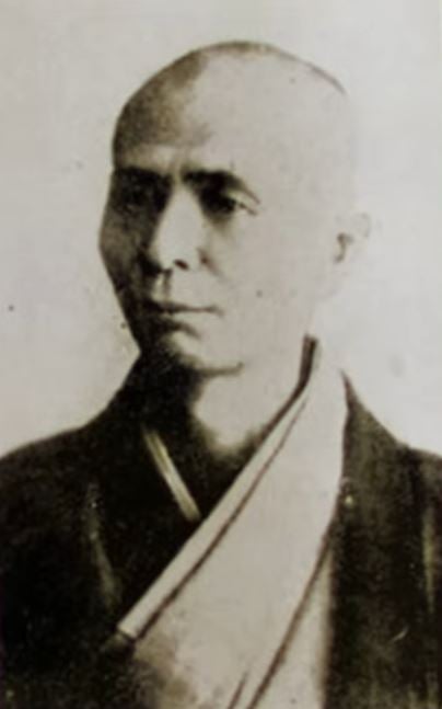Black-and-white portrait of a bald man in traditional clothing associated with the world of Go.
