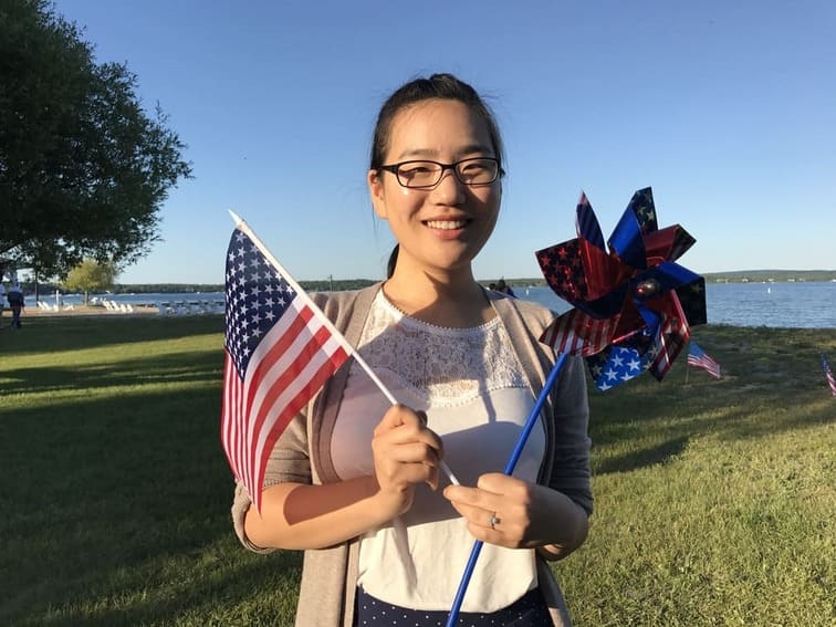 Hajin Lee smiling outdoors holding an American flag, celebrating cultural exchange and Go’s global spirit