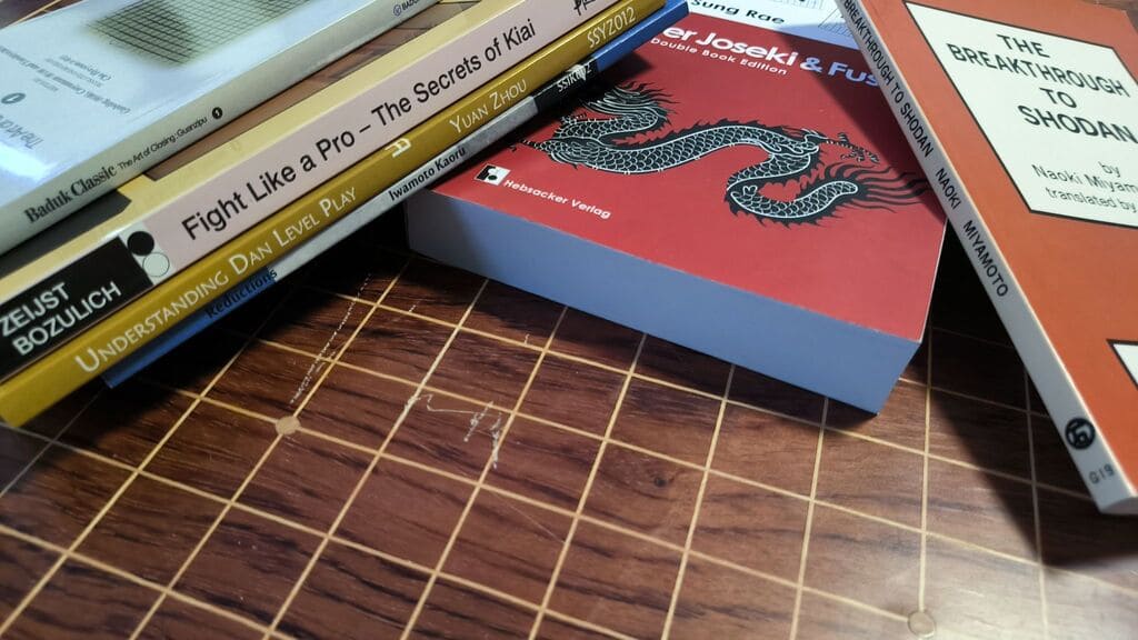 Several advanced Go books arranged on a Go board surface