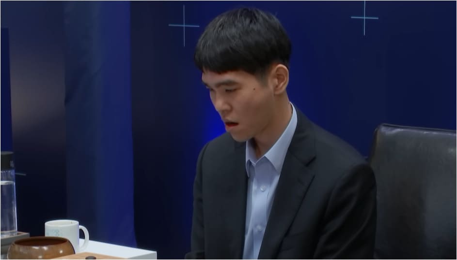 Close-up of a professional Go player looking shocked or deeply surprised during the AlphaGo match.