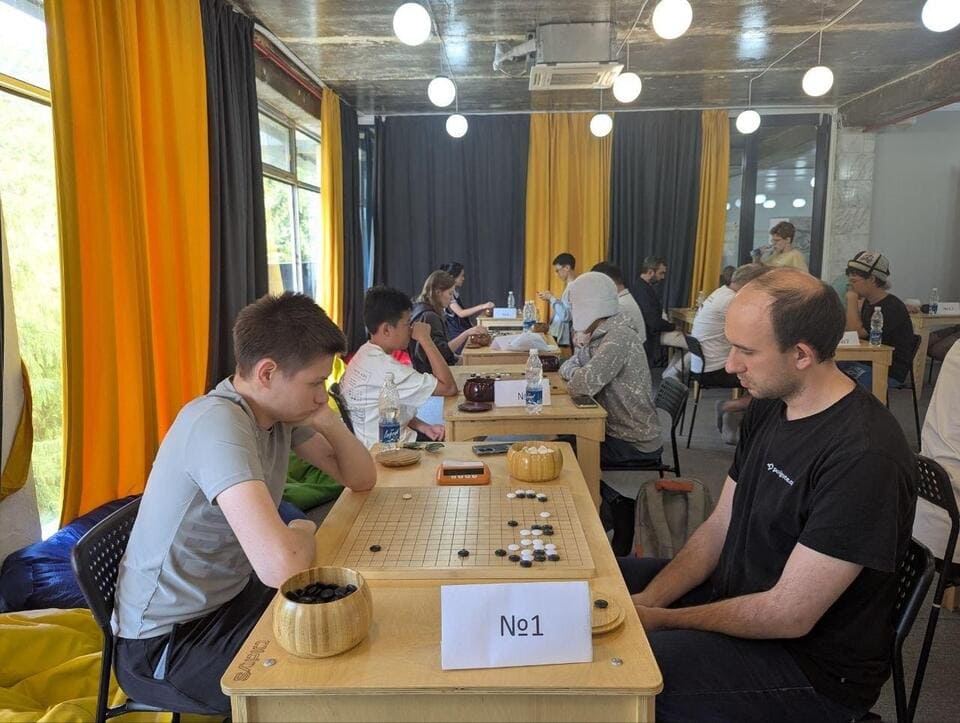 Players seated across Go boards in the tournament room during the Issyk-Kul Cup.