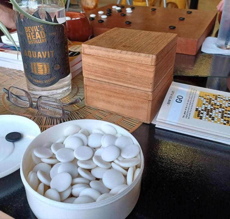 Contemporary Go setup with polished board, bowls, and arranged game in progress.