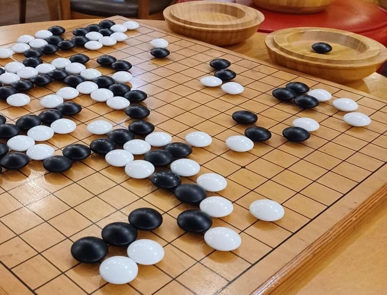 A classic Go game with traditional black and white stones during mid-play.