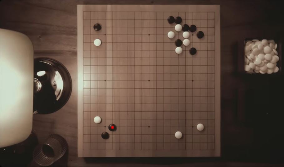 Top-down view of a Go board with a sparse opening position and a few black and white stones placed in different corners.