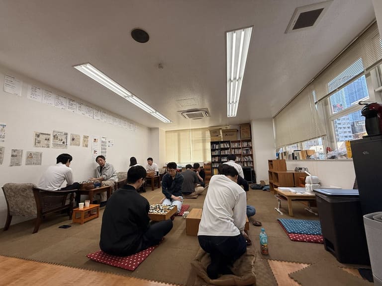 Several players sitting on floor cushions and playing Go in a quiet club room