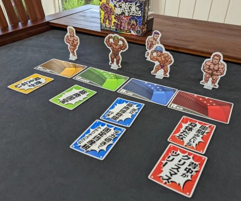 A bodybuilding-themed card game in progress with muscular character standees and colored cards.