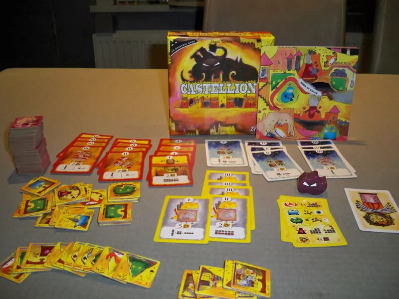 The board game Castellion laid out, showing cards, tokens, and the game box with vibrant colors and intricate artwork.