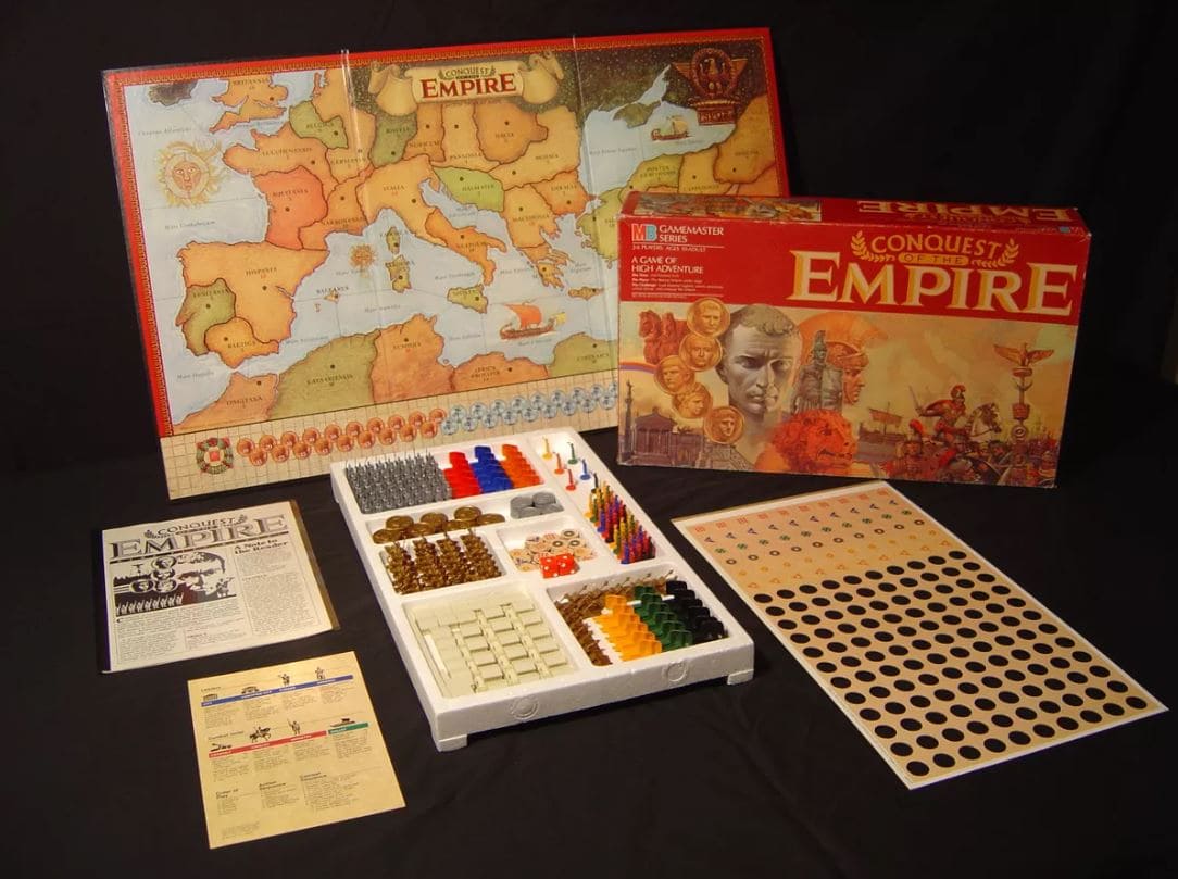 A photograph of the 1980s edition of "Conquest of the Empire," showing the game board of ancient Rome, detailed game pieces, and instruction manuals.