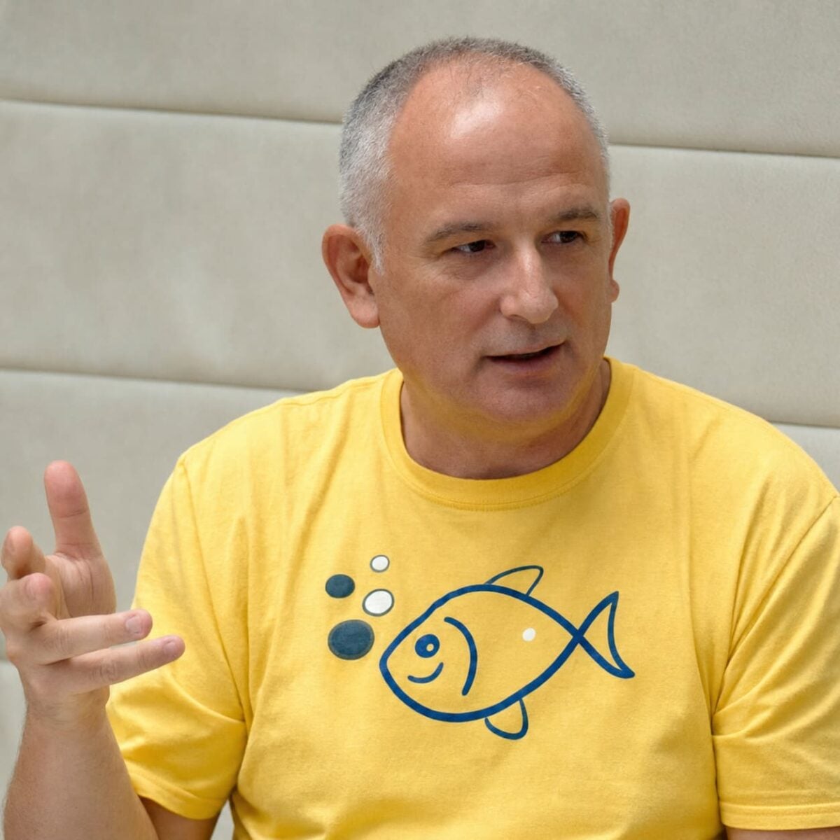 Prof. Dr. Damir Medak speaking and gesturing in a yellow T-shirt