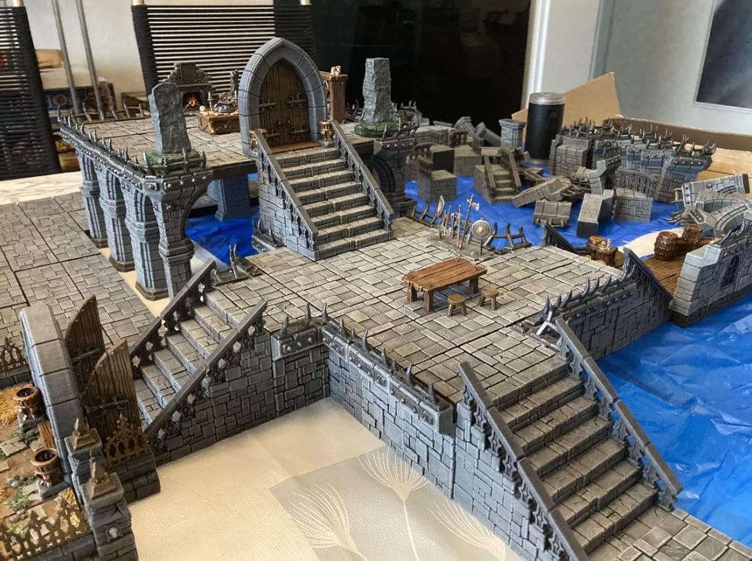 A close-up of the intricate 3D terrain from Descent: Legends of the Dark, featuring a dungeon with stairs, archways, and various miniature elements.