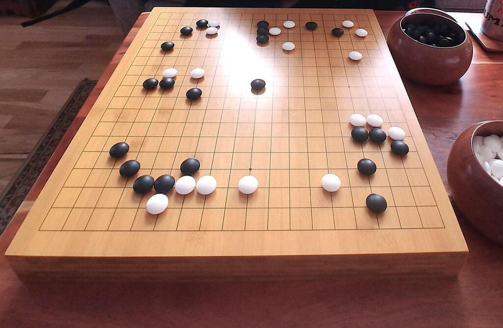 Bamboo Go board with black and white stones, placed in a cozy indoor setting