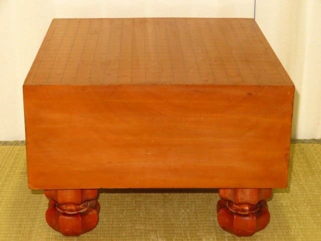 Reddish-brown Go board on traditional tatami mat, likely made of katsura or cypress
