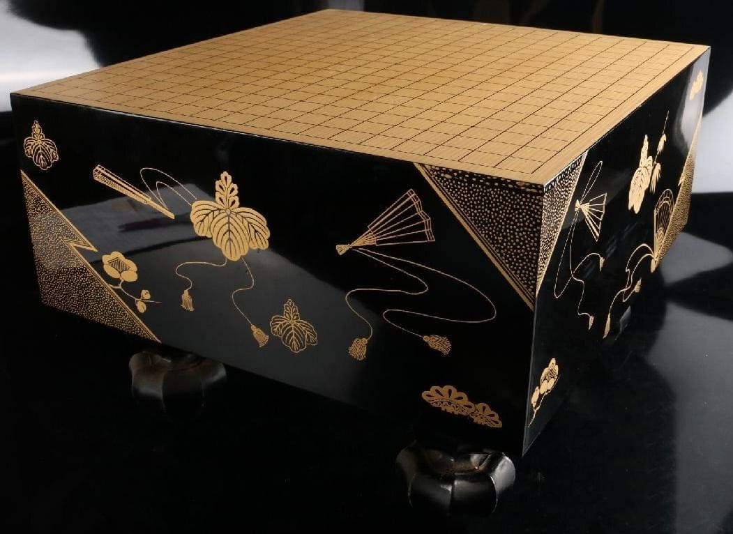 Black lacquered Go board with traditional Japanese gold decorations on the sides