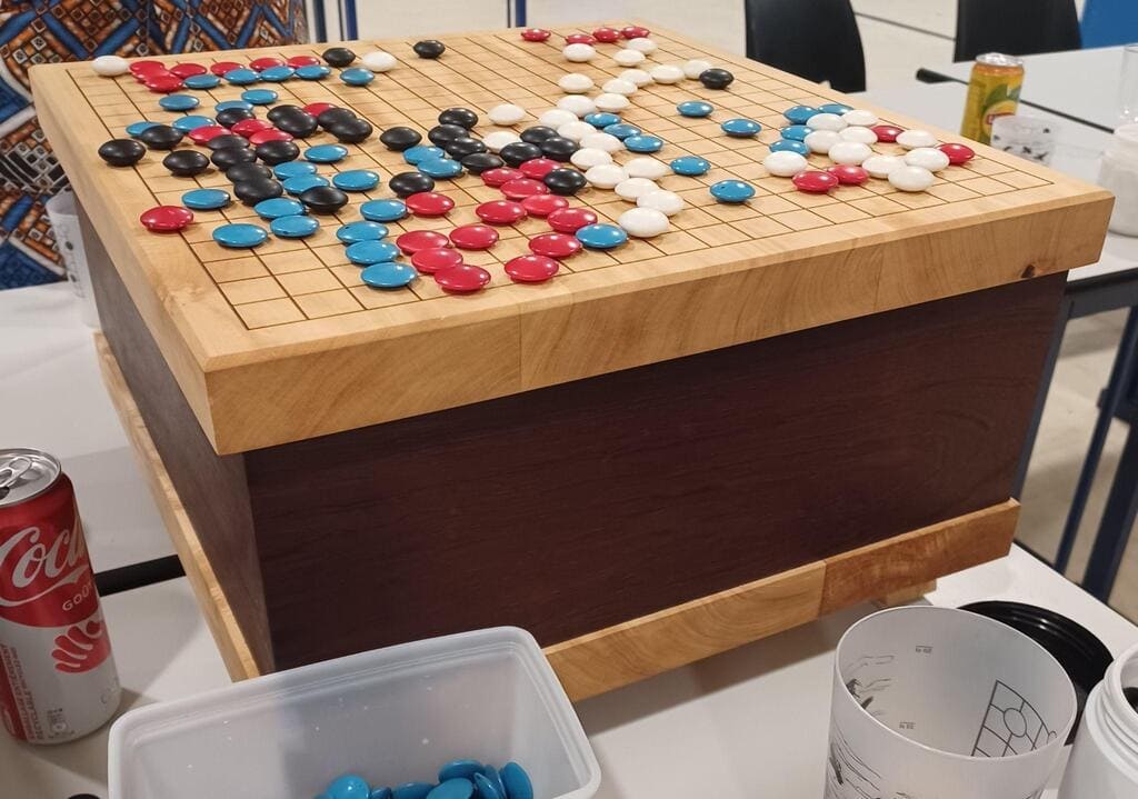 A Go board filled with black, white, red, and blue stones in a casual indoor setting