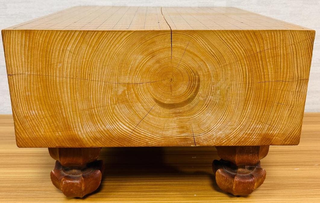 Side view of a solid wood Go board highlighting tree rings and natural cracking