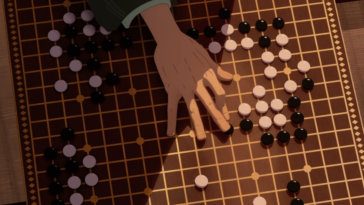 A close-up of a hand placing a stone on a Go board, with black and white stones scattered on the grid.