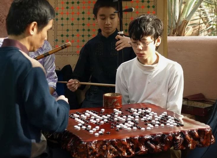 Two people engrossed in a game of Go, surrounded by traditional elements of the game.