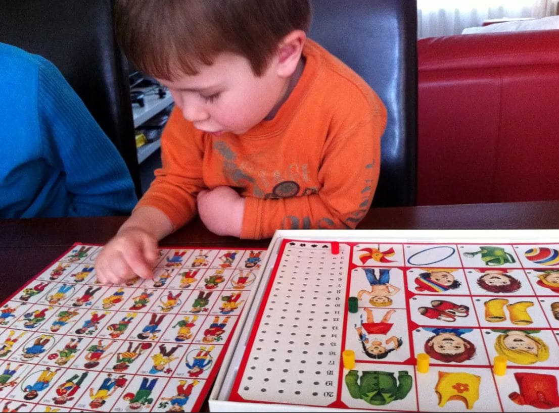 A child carefully selecting a character in the classic game Guess Who.