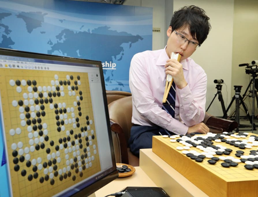Iyama Yuta reviewing a Go game with the help of AI analysis displayed on a screen