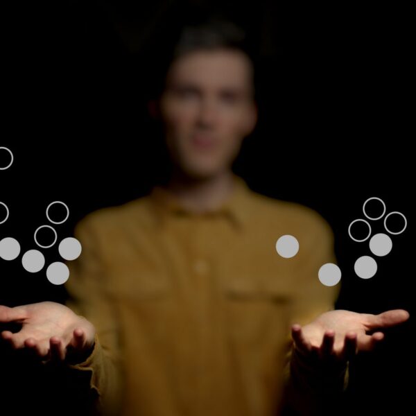 A blurred man in a yellow shirt holds out his hands as animated Go stones appear to float and orbit between them in a dark background.