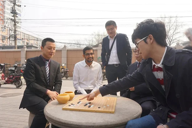 Ke Jie playing an outdoor Go match with Nie Weiping, Fan Hui, and Gu Li, while enjoying a casual and friendly discussion.