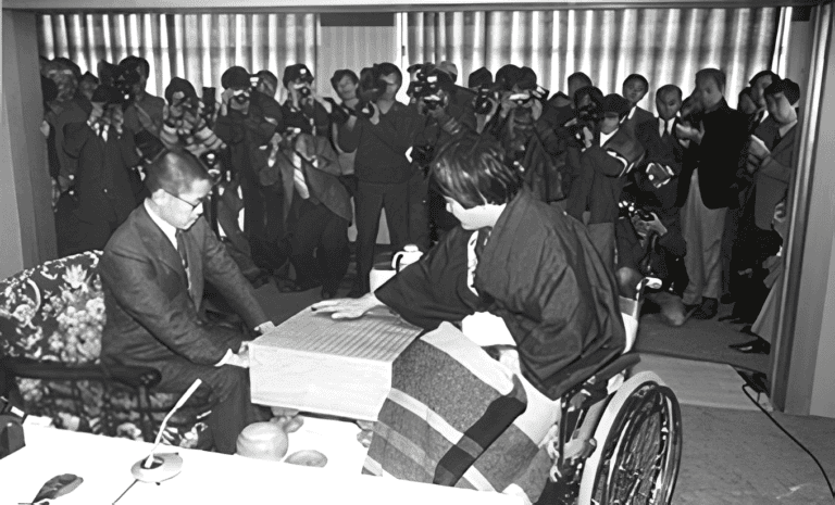 Legendary Go players Cho Chikun and Kobayashi Koichi face off at the Kisei title match, with a large crowd of press and spectators in the background capturing the iconic moment.