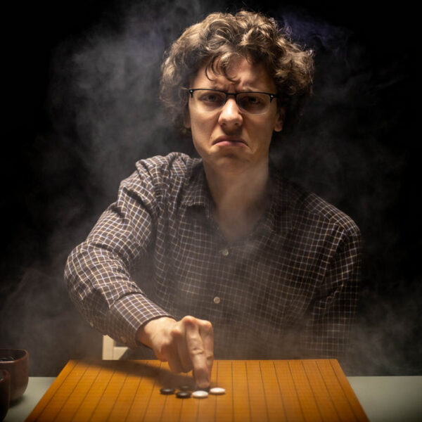 Serious man playing Go surrounded by theatrical smoke