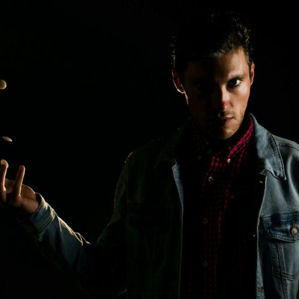 A dramatic photo of a man tossing white Go stones in low light